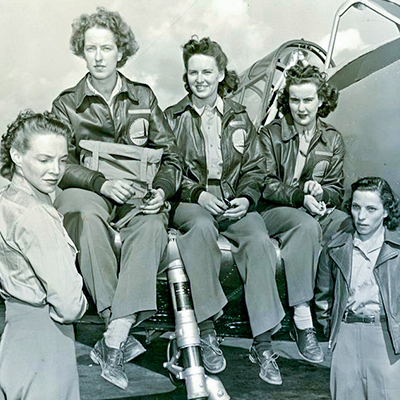 Women aviators pose in front of an airplane