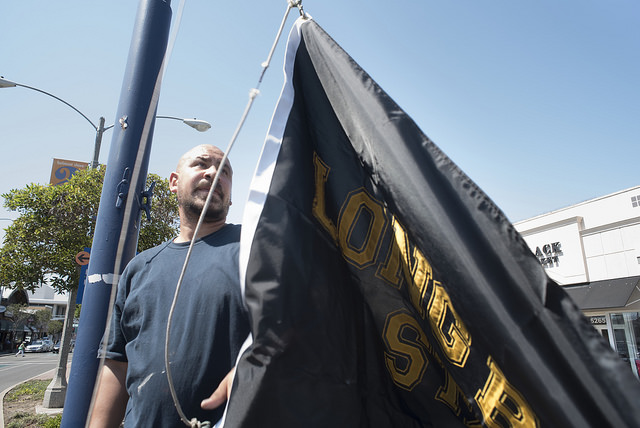 A worker hangs a CSULB flag on 2nd Street
