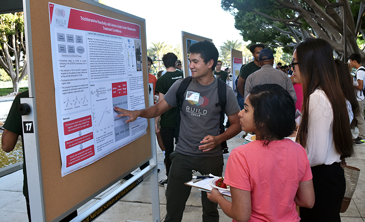 Year Two Scholar Landon Watts explains his research to atten