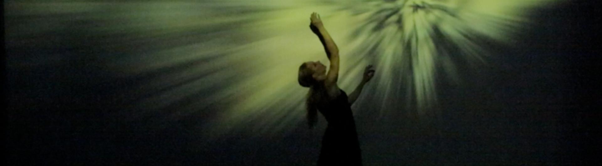 Francesca dances in front of green projection