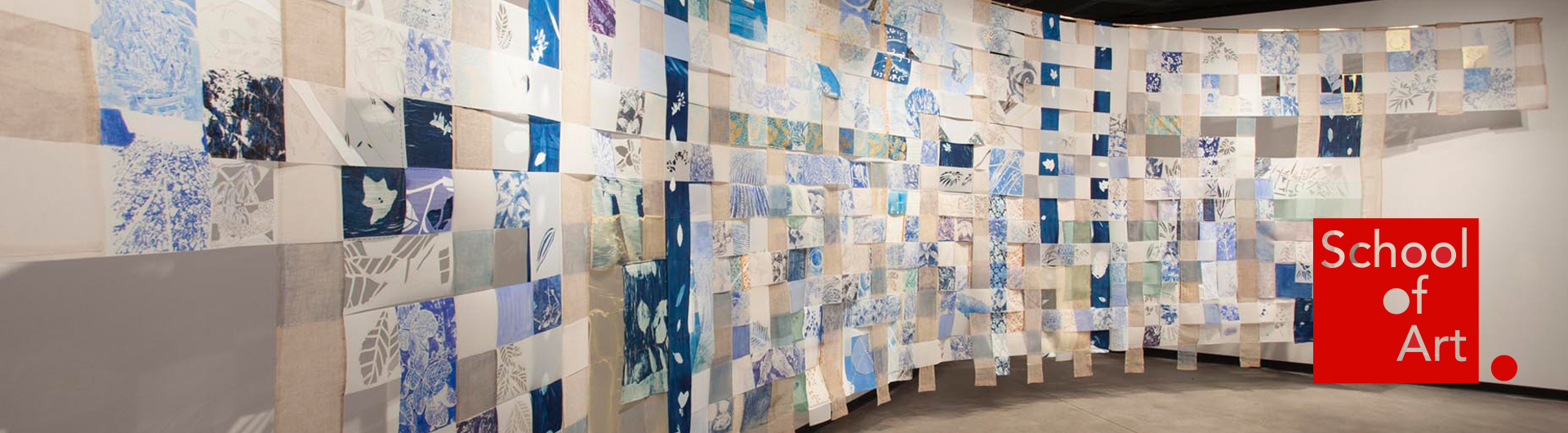 Interwoven strips of fabric hung on a gallery wall