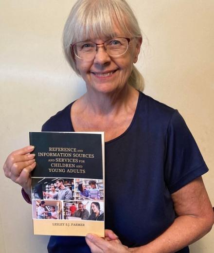 Photo of a woman, Professor Lesley Farmer, holding a book
