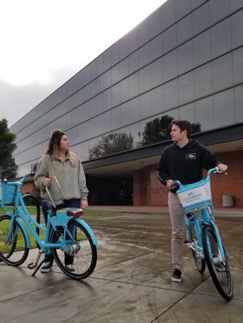 Two students riding on bike share bikes