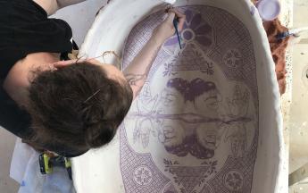 Artist in residence Nicki Green doing intricate glaze decoration on a large basin form, 2019.