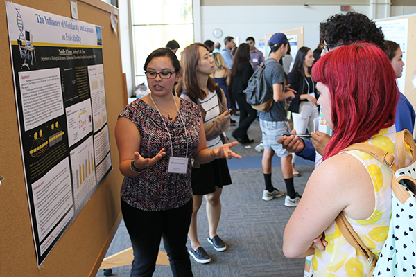 student researcher explaining her research to other students