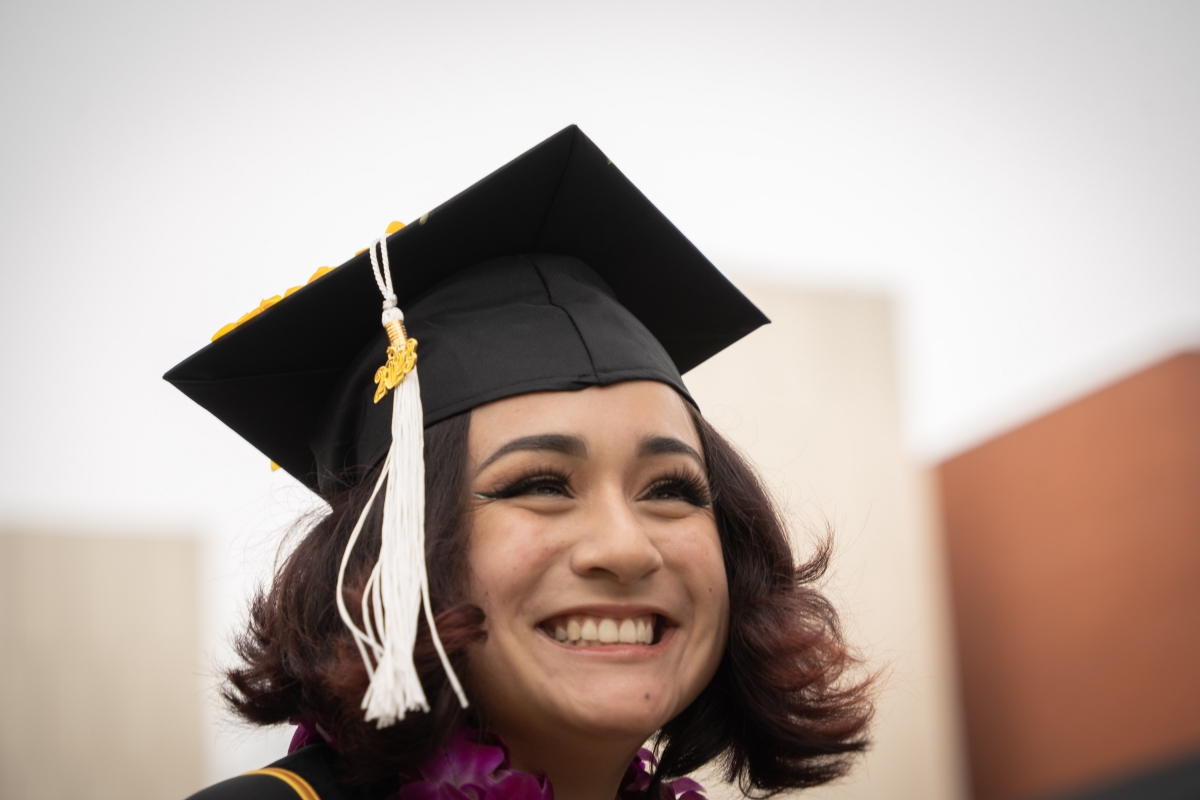 Student smiles wearing graduation cap.