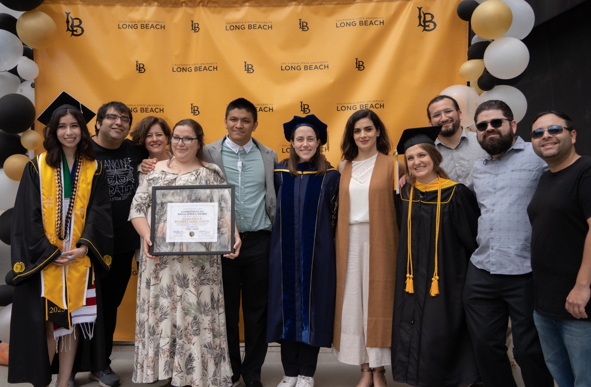 Group of students and faculty faces forward smiling at graduation ceremony.
