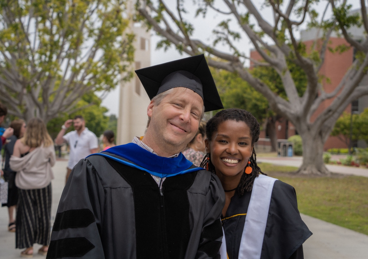 Dr. Fender and a student stand smiling at graduation ceremony.