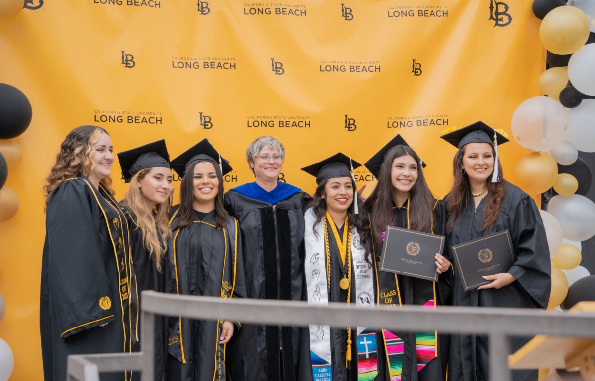Group of students and faculty smiling at grad ceremony.