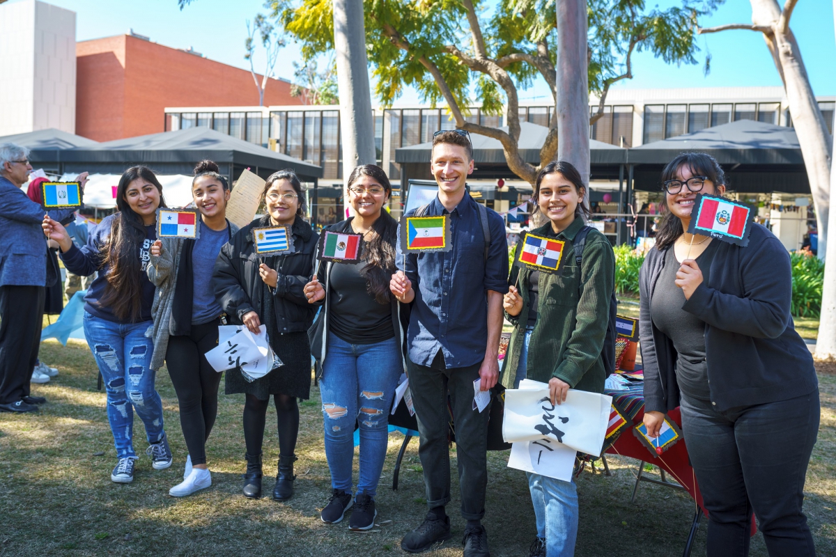 Group of people stand with various national flags representing the varying languages and cultures.