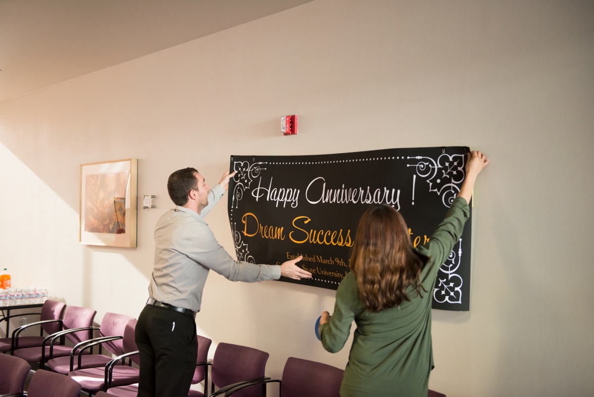 Dream Success Center anniversary banner being hung on wall