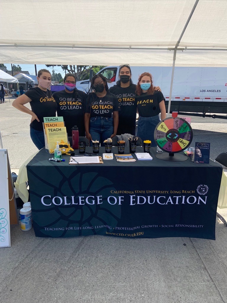 Students are outside behind a table. 