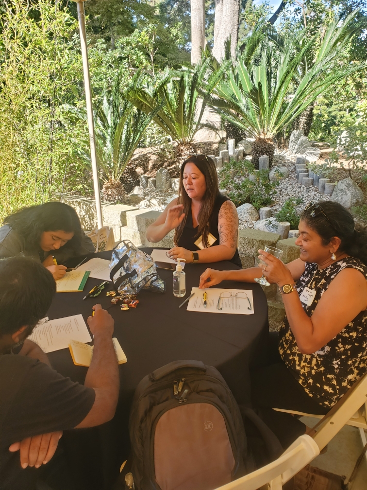 A group of people talking and writing notes at a round table