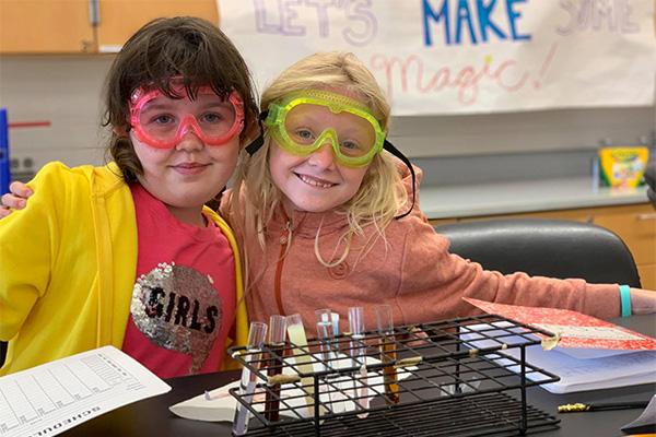 two campers smiling over a test tube rack