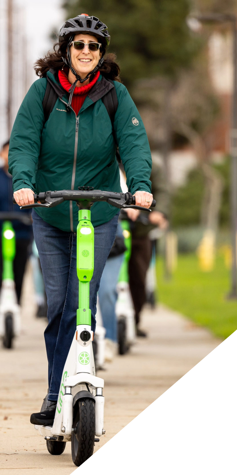 A woman rides an electric scooter on campus. 