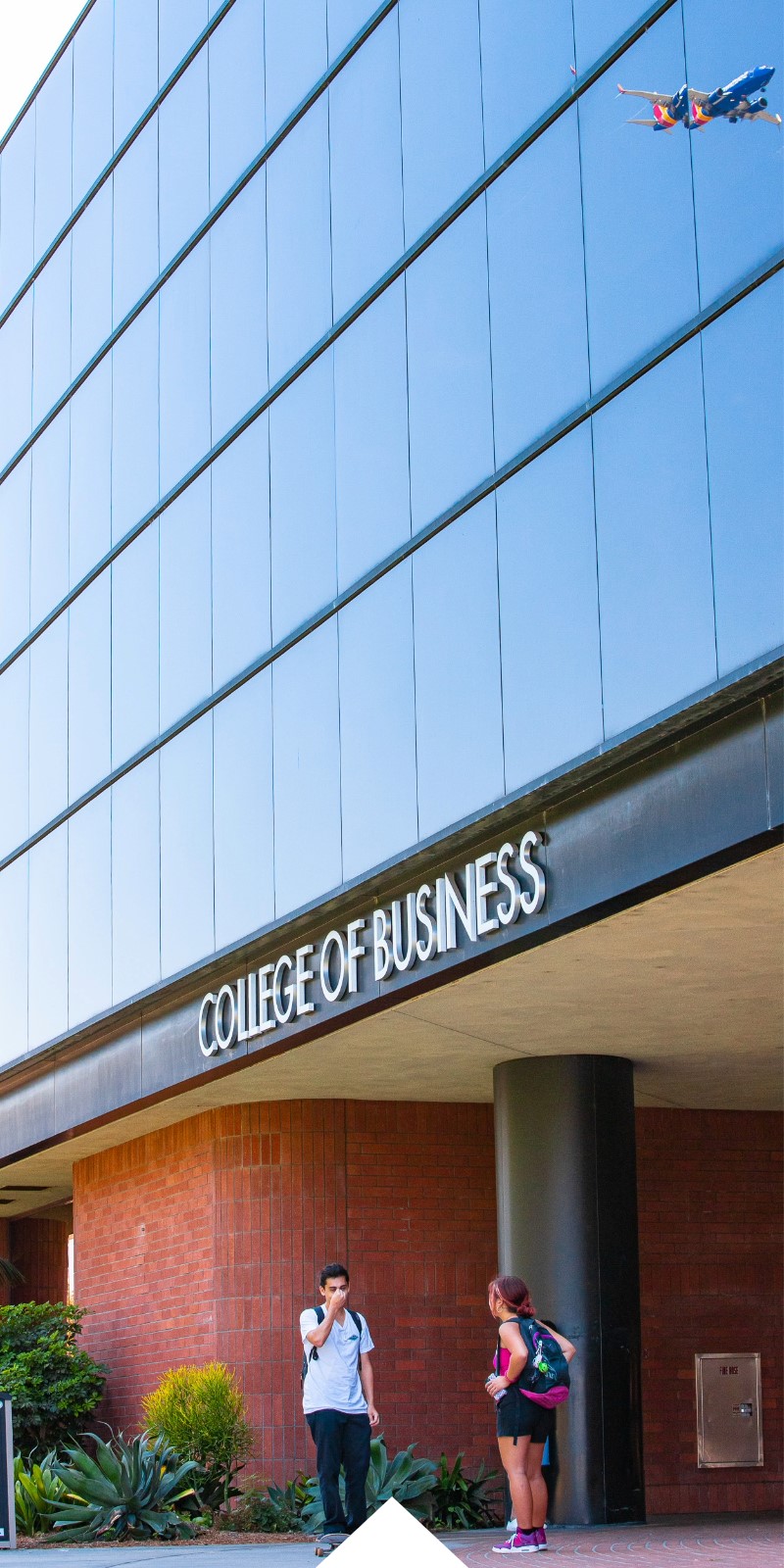 Two students talk outside of the College of Business building.