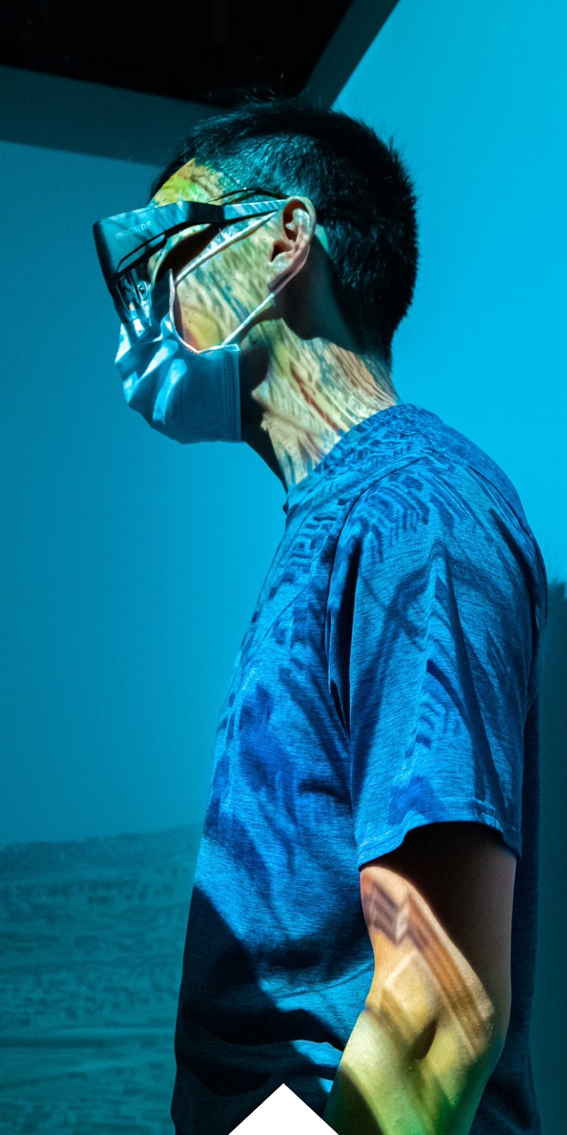 A student in glasses in surrounded by a blue hue during research week.