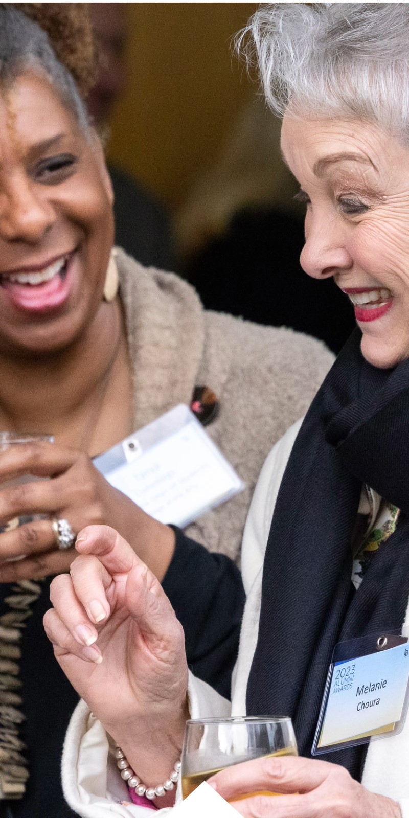 Two woman laugh during the alumni awards ceremony.