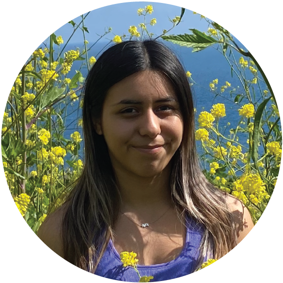 A photo taken of Gizelle Vallejo in a field of tall, yellow flowers.