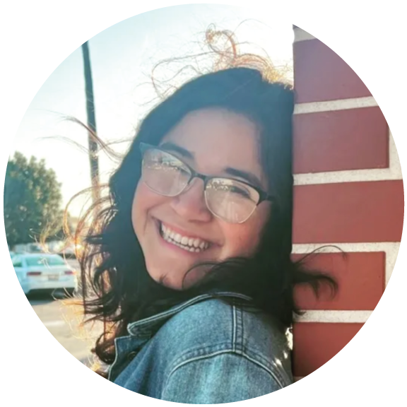 A photo taken of Laura Escobar, leaning against a brick wall.