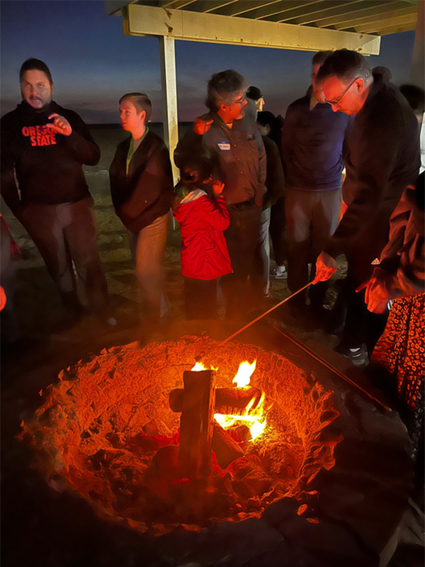 people gathered around a beach firepit
