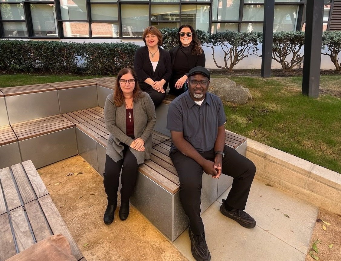 Four staff members standing under sun shade