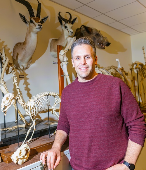 Ted Stankowich standing in front of various skeletons and taxidermy heads