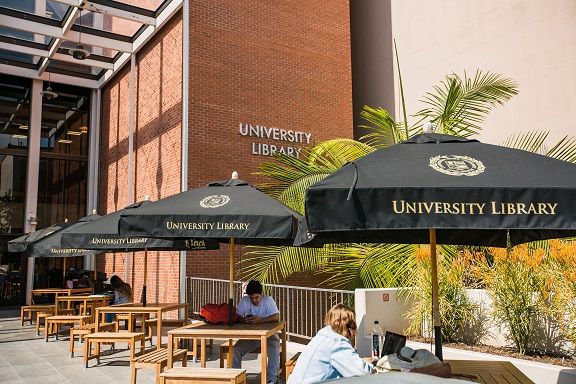 Front of Library entrance patio tables and umbrella.