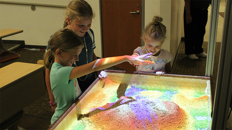 young children playing with augmented reality sandbox