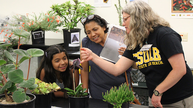 botanist talking to a mother and daughter about an orchid