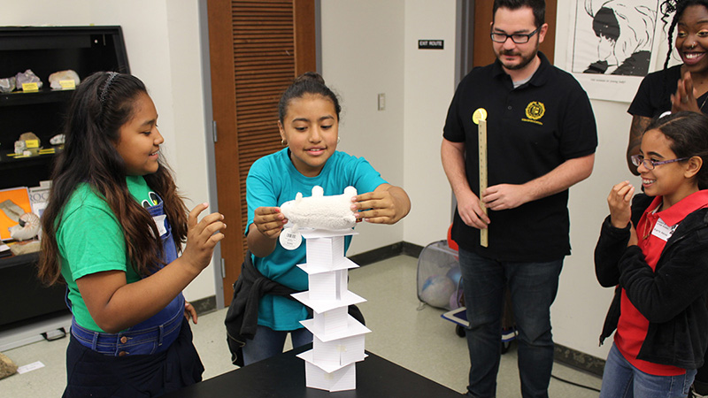 young kids testing the strength of a tower made from index cards