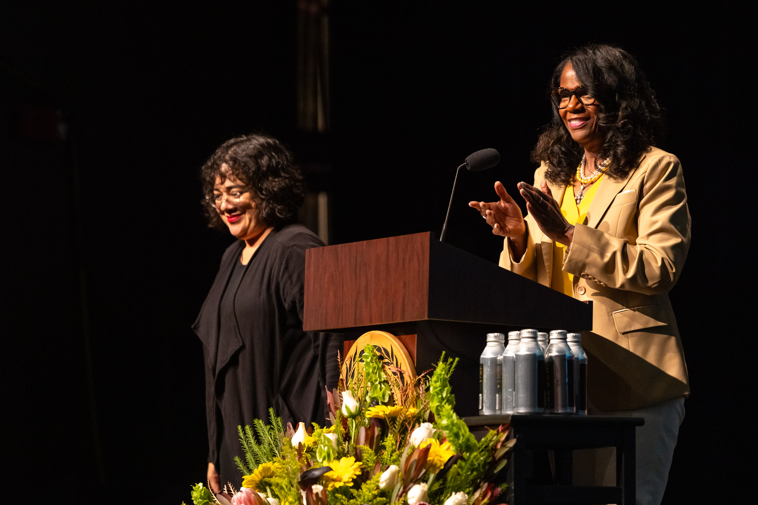 A sign language interpreter standing next to Provost Karyn Scissum Gunn, who is standing behind a podium