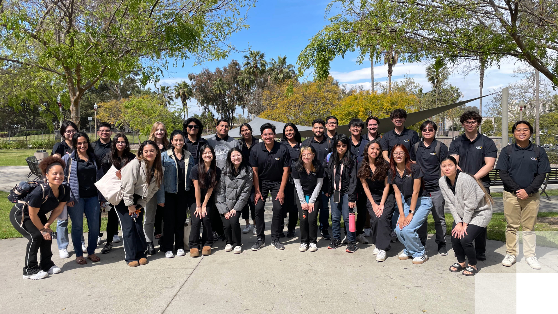College of Business VITA program. A group of students smile and pose surrounded by trees.