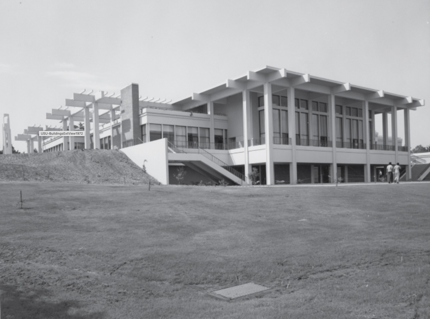 Student Union right after it was built A modern two-story building with large windows and columns stands on a grassy hill.