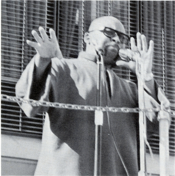 Maulana Karenga person with glasses speaks passionately on campus Maulana Karenga person with glasses speaks passionately, raising both hands at a microphone.