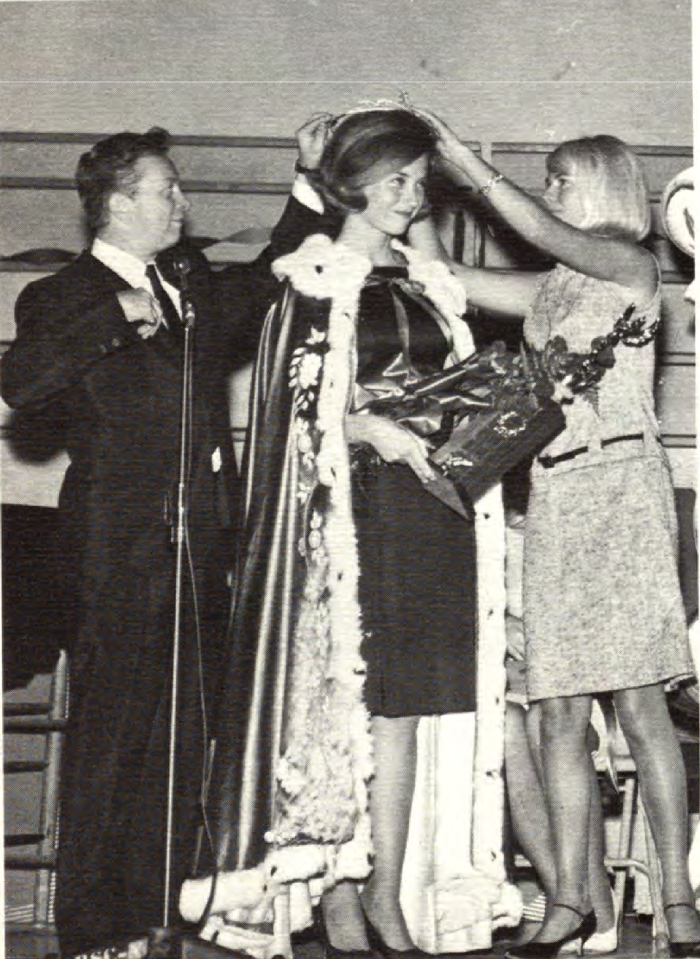 Mel Torme crowns homecoming queen in 1965. A person is crowned while standing in a fur-trimmed robe and holding a bouquet.