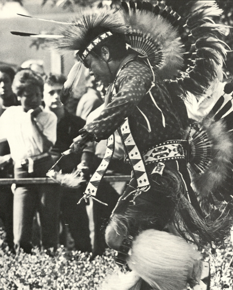 Early CSULB Pow Wow A dancer in traditional Indigenous regalia performs in front of a crowd.