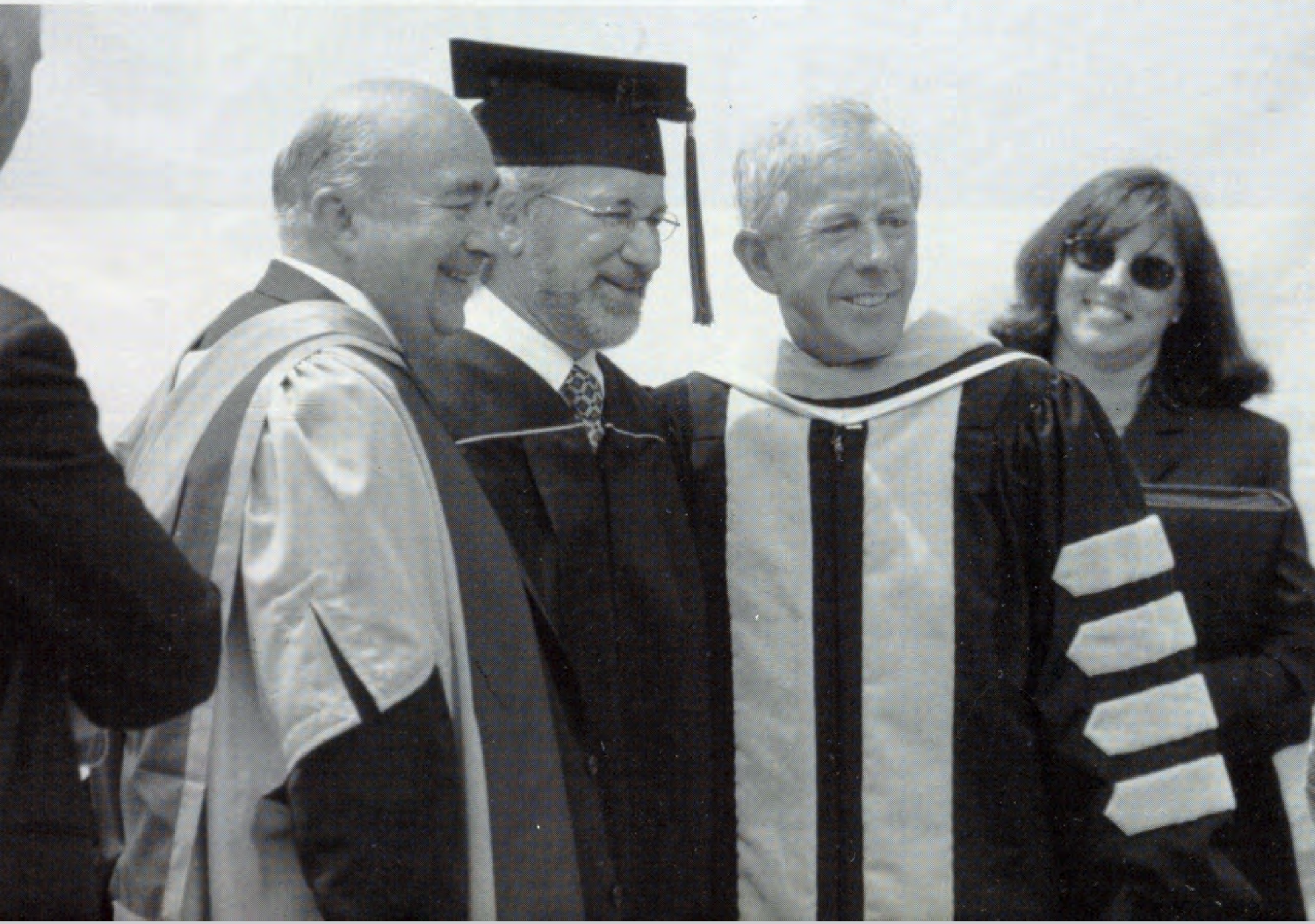 Steven Spielberg receives his diploma Three people in academic robes smile at a graduation ceremony.