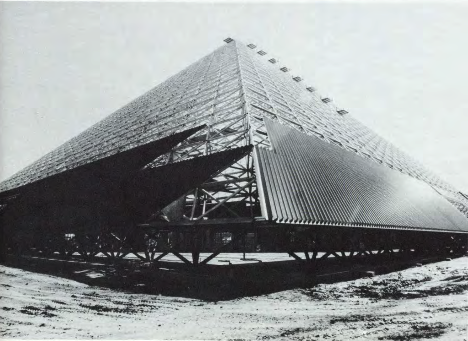 Construction on the Walter Pyramid The steel frame of a large pyramid building under construction, set against a cloudy sky.