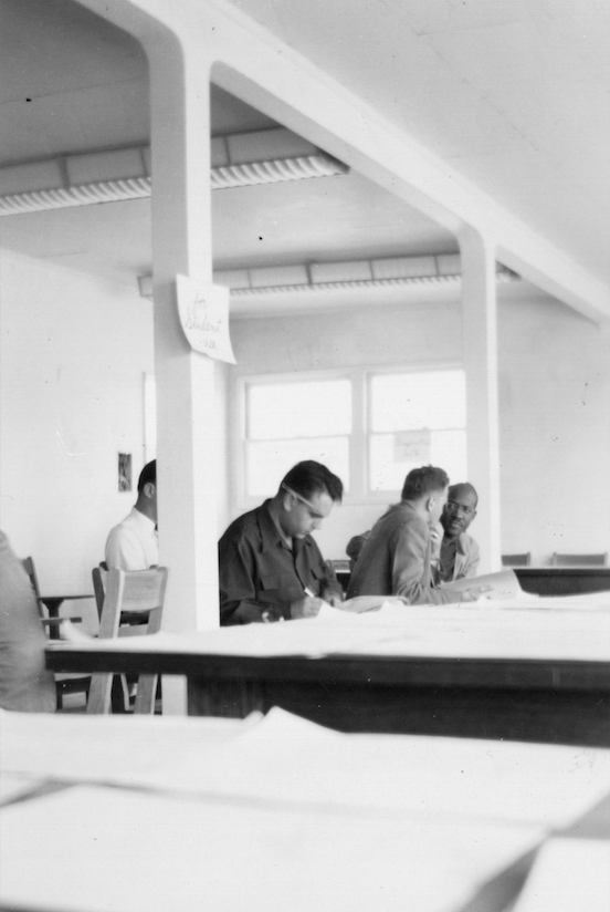 Students registering for CSULB classes, early 1950s. Students sit at tables in a large room and fill out forms.
