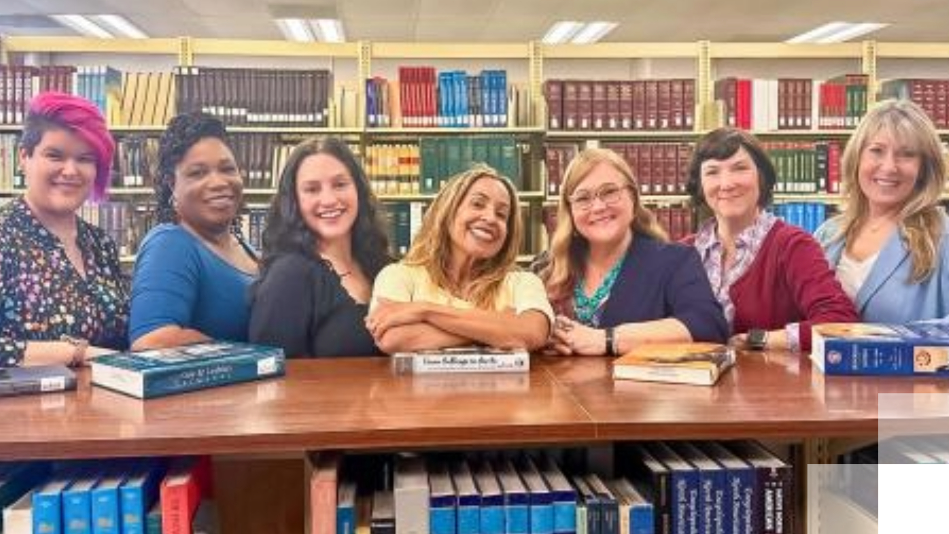 University Library - Beach 2030 Women smile in front of book case.