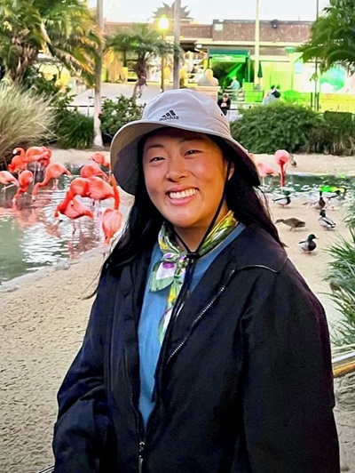 Sharon Kim Sharon Kim standing in front of a group of pink flamingos