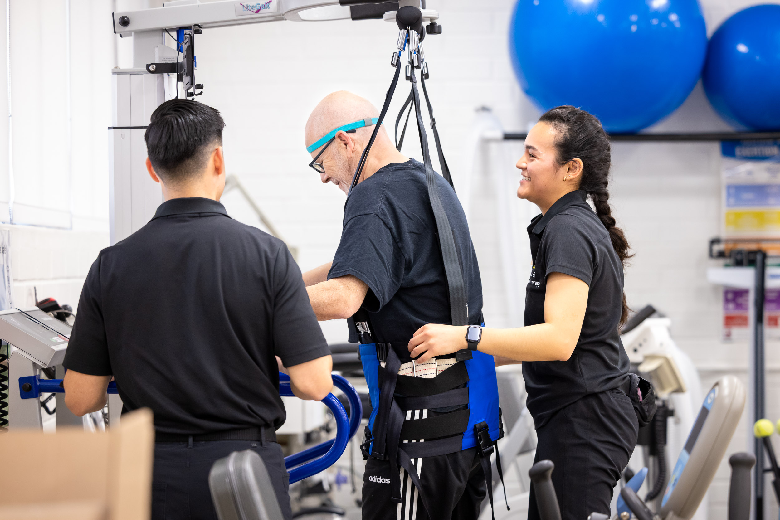 Two students help a patient in the Neuro Clinic walk on a treadmill