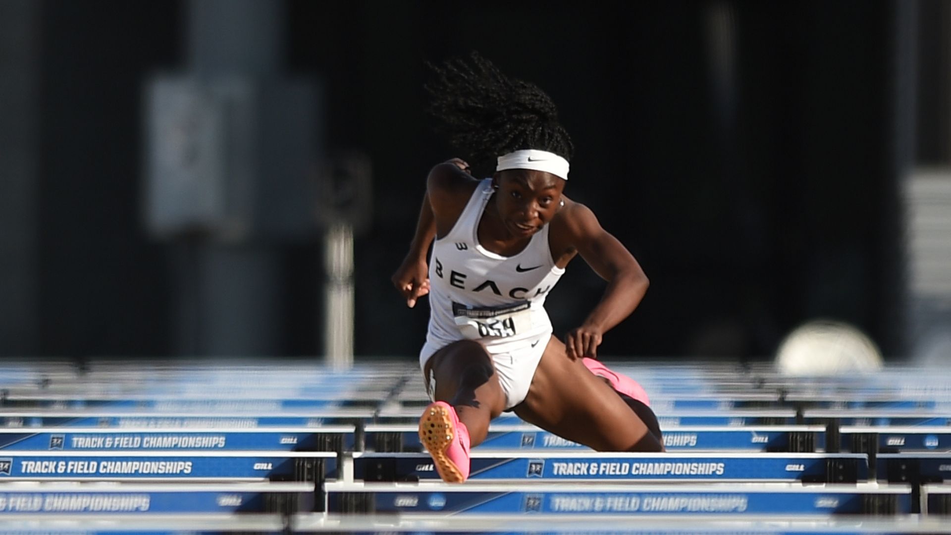 Athlete in midair clears a hurdle during a track and field race. Athlete in midair clears a hurdle during a track and field race.