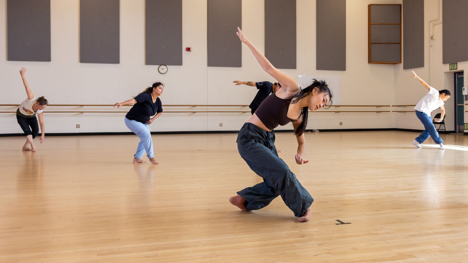 Dancers in a studio at CSULB Dancers in a studio move expressively across a hardwood floor during rehearsal.