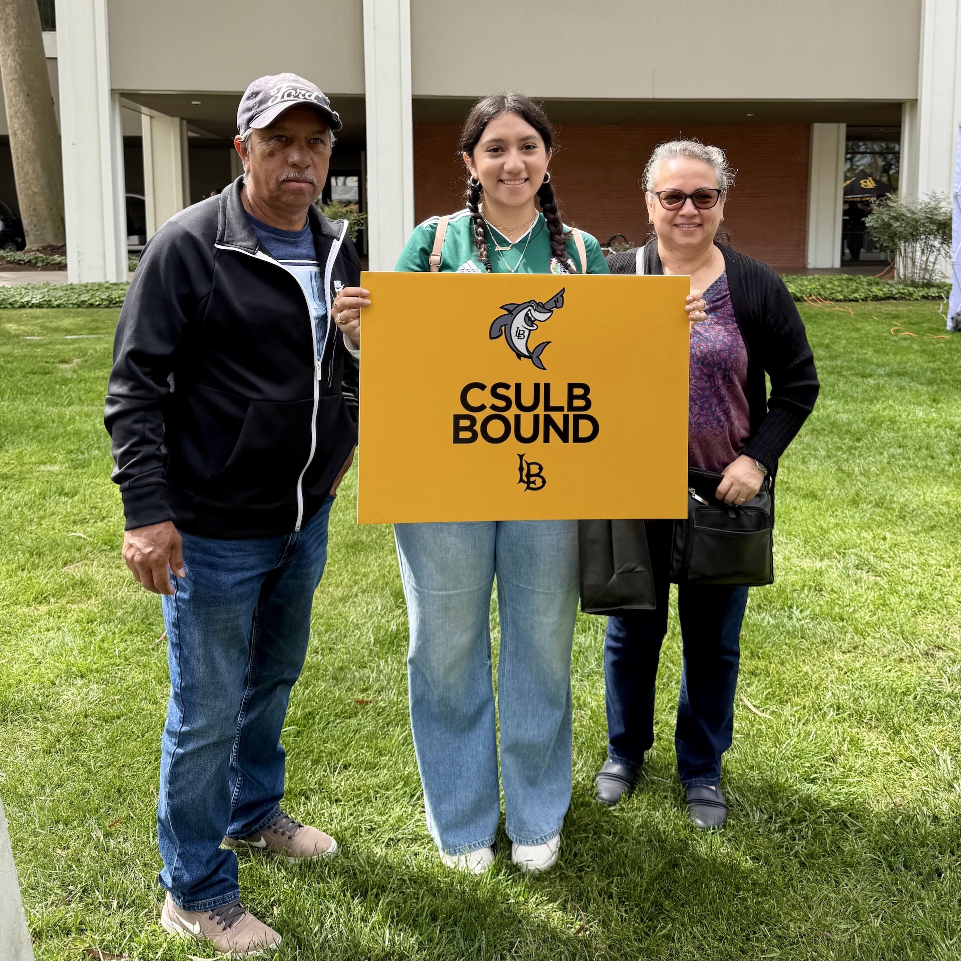 Student holds CSULB Bound poster flanked by her parents
