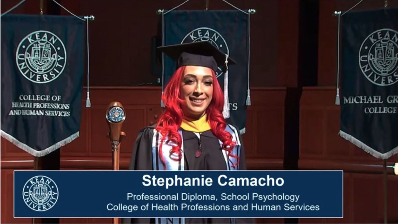 Graduate in black cap and gown with name displayed below