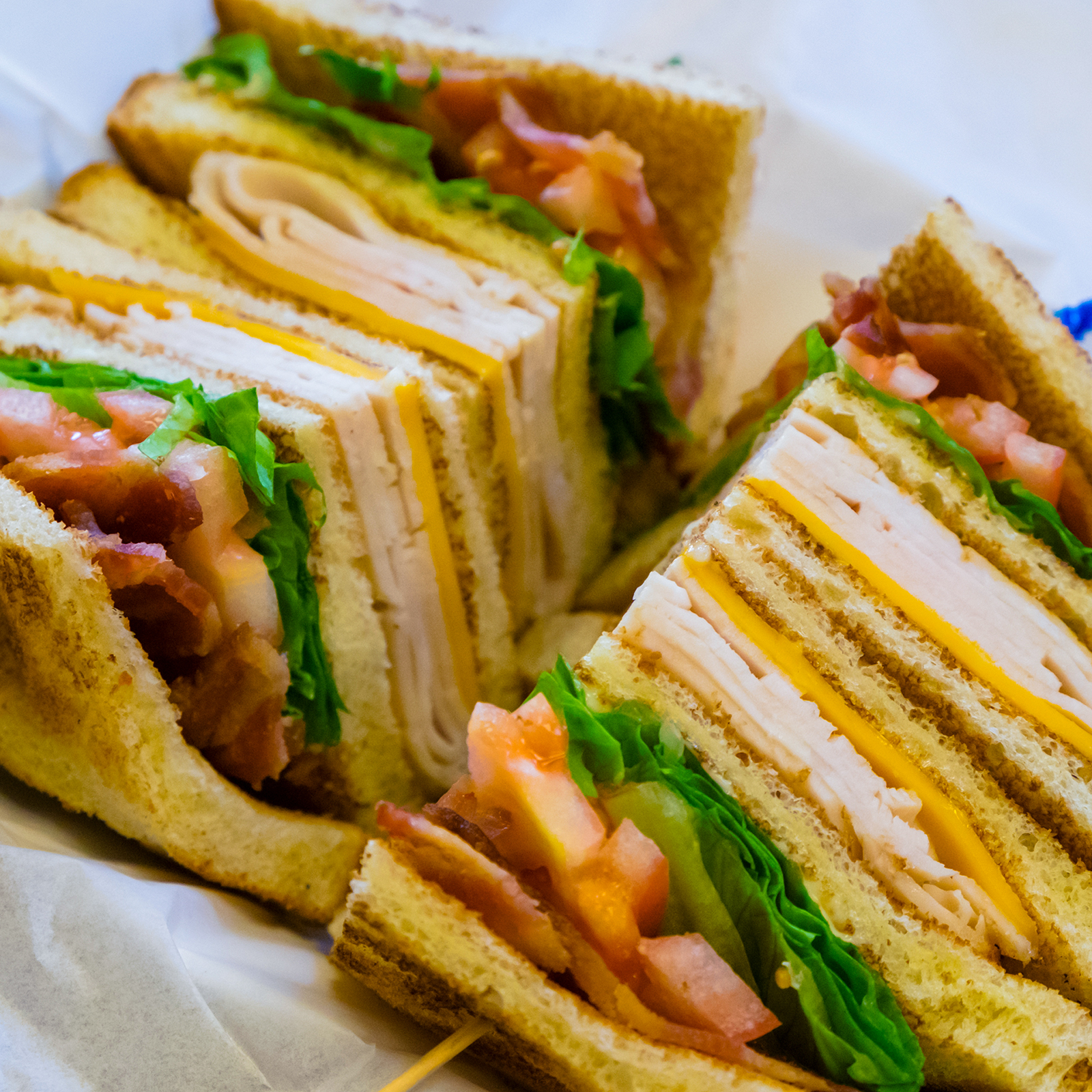Large sandwich with multiple layers of meat and cheese and condiemnts. 