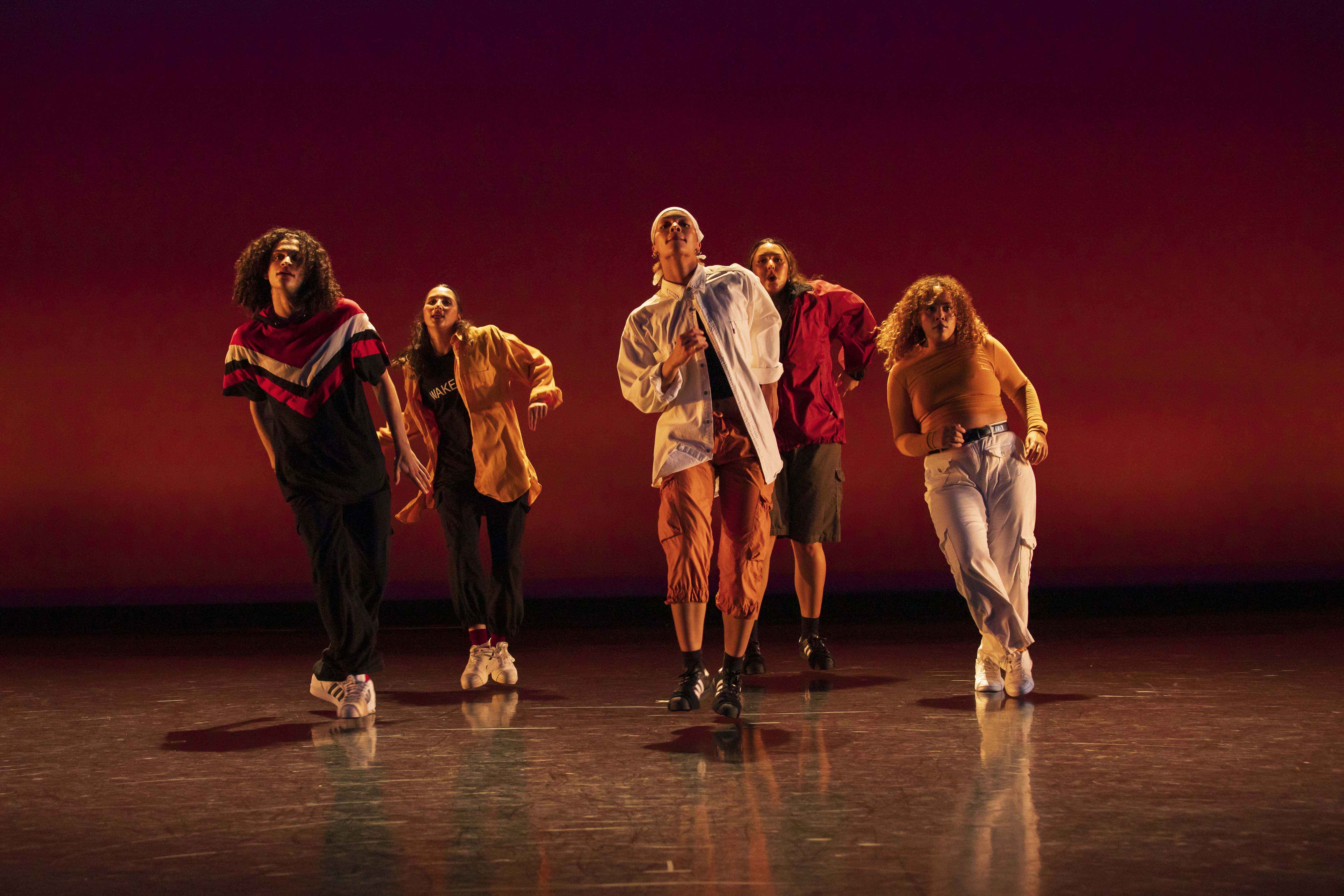 Five dancers perform on stage.