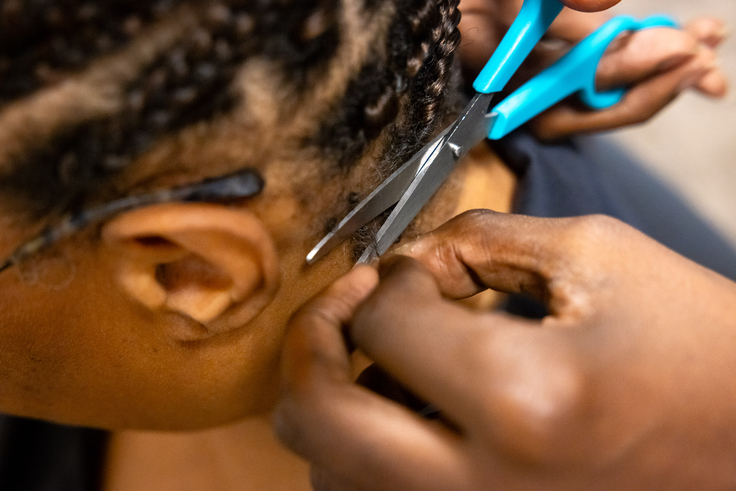 Hands holding scissors while cutting hair